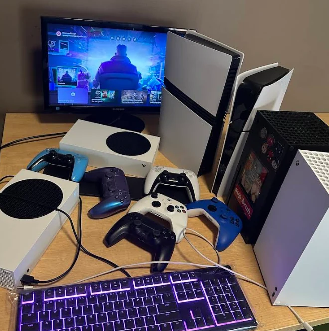 FlexRepairs lab bench setup with PS5, Xbox Series X, Series S consoles, controllers and test monitor
