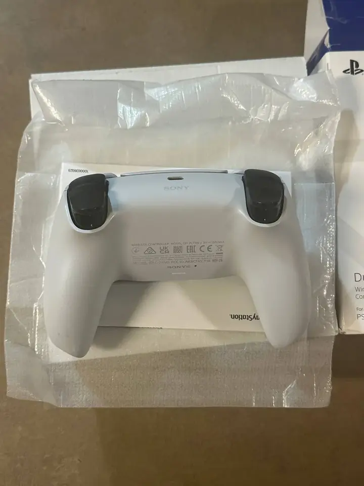 Back of a white PS5 DualSense controller showing the triggers and model label