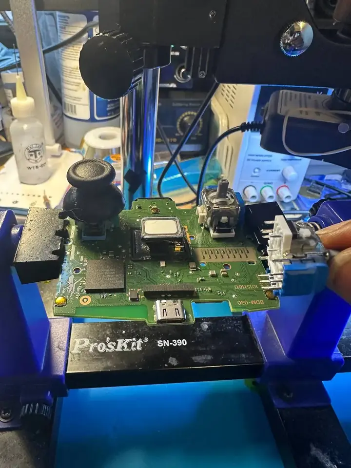 DualSense controller board held in a ProsKit board holder during joystick replacement