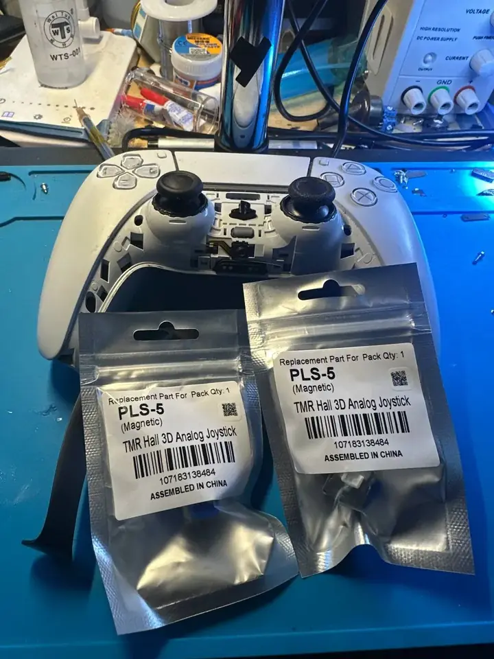 PS5 DualSense controller beside two TMR Hall-effect magnetic joystick replacement parts