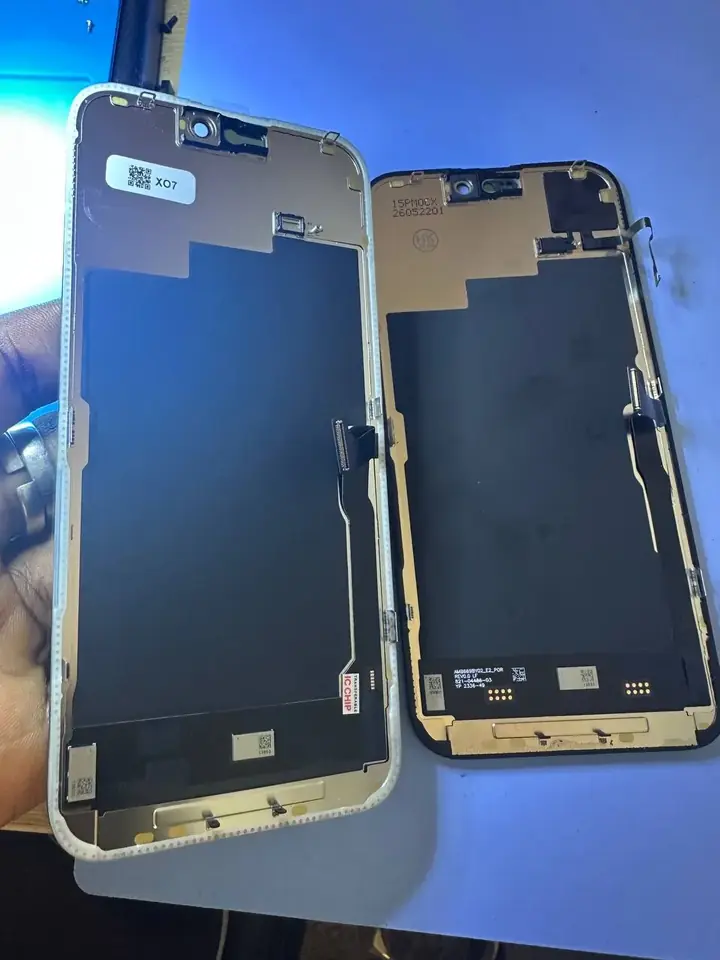 Replacement iPhone 15 Pro Max display panel held beside the original screen