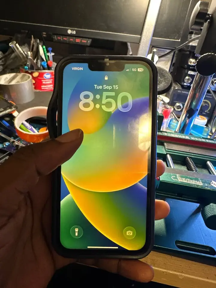 Repaired iPhone held at the FlexRepairs Oshawa bench showing a bright, clear lock screen after screen replacement