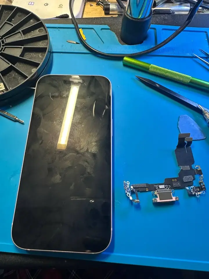 Removed iPhone USB-C charging port flex cable beside the phone on the repair mat