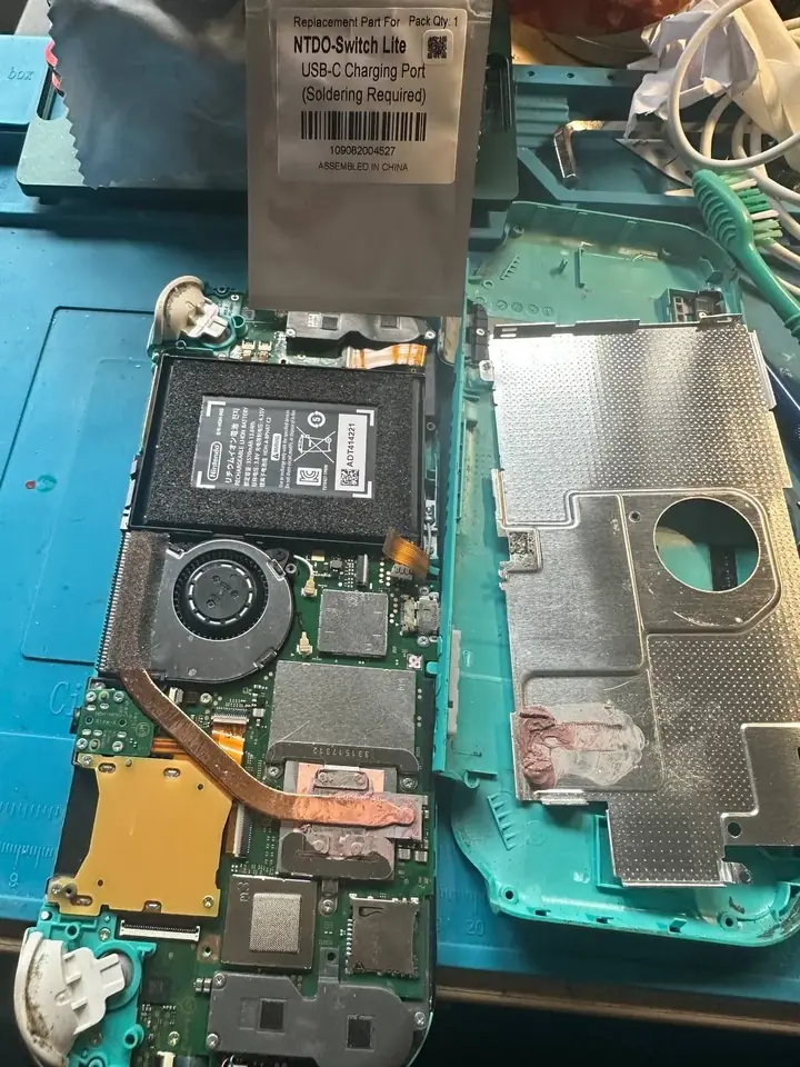 Switch Lite USB-C charging port replacement part above the opened console motherboard