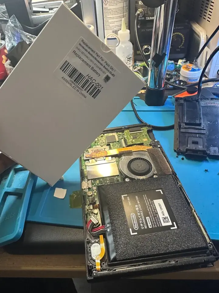 Replacement HAC-001 battery for the Nintendo Switch and Switch OLED beside an opened console
