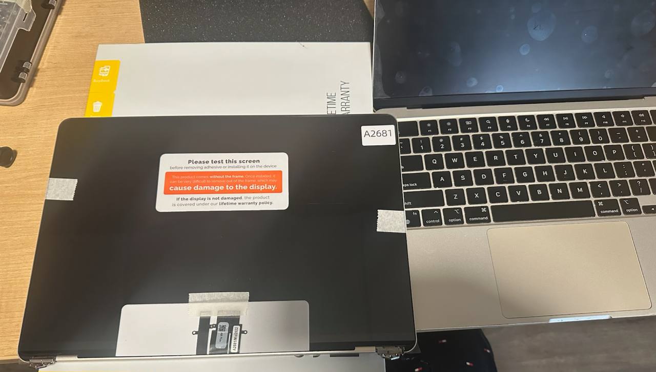 Replacement MacBook display panel prepared beside the laptop