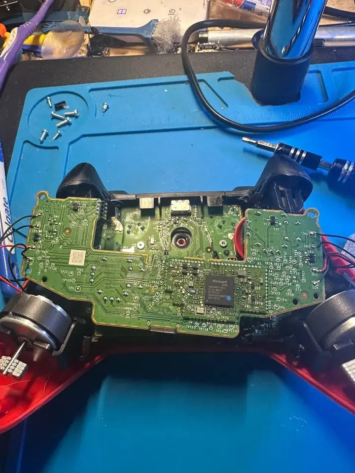 Xbox Series controller opened in a red shell with its main board, triggers and rumble motors exposed