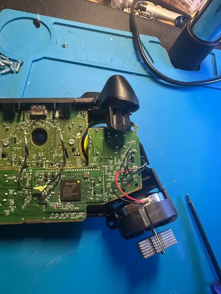 Close-up of an Xbox controller board, trigger and rumble motor during repair