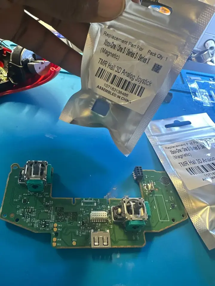 TMR Hall-effect magnetic joystick replacement part beside an Xbox controller board
