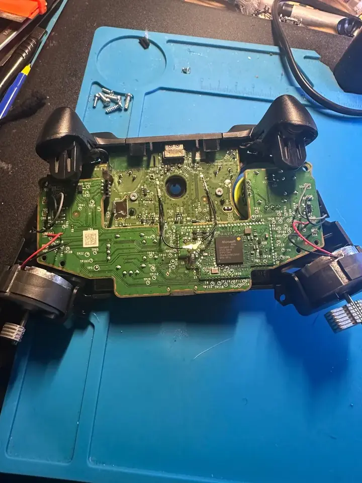 Xbox Series controller motherboard with rumble motor wiring on the repair mat